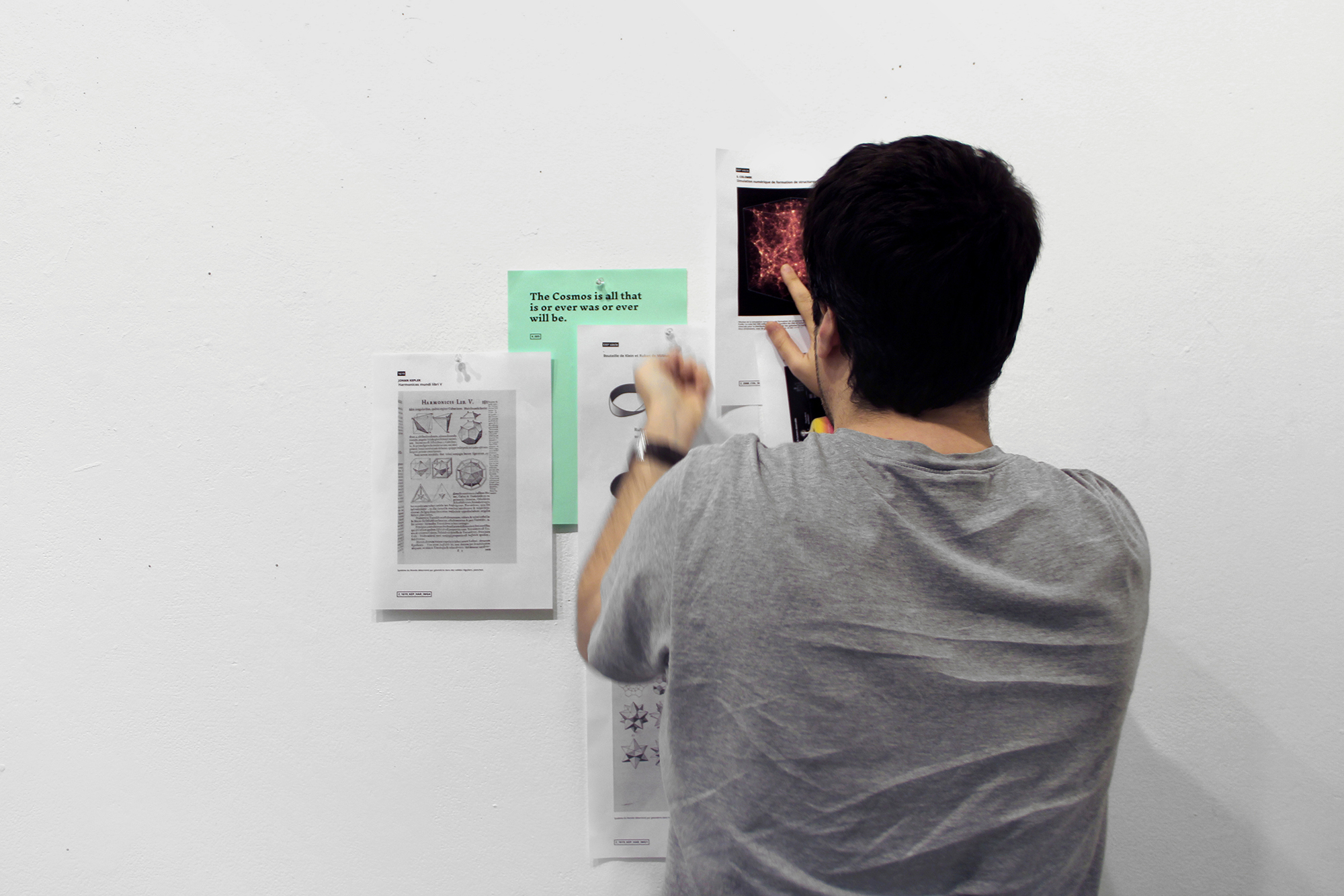 Photographie d'un workshop: participant accrochant des feuilles au mur